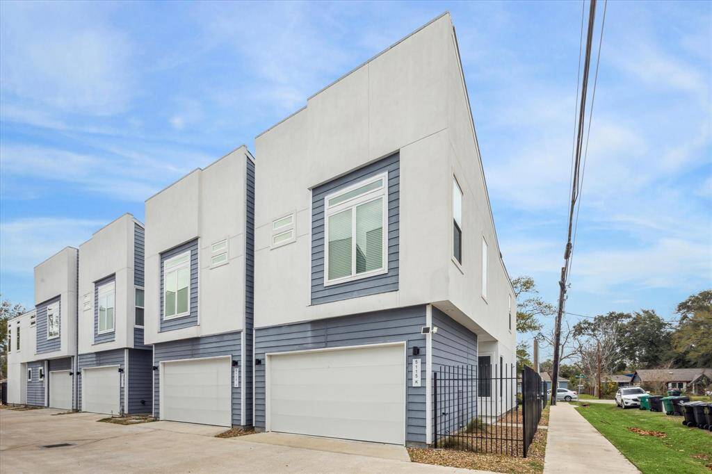 Modern home with a sleek exterior design, featuring a two-car garage and large windows. Located in a well-kept neighborhood with a clean, spacious driveway and minimal landscaping.