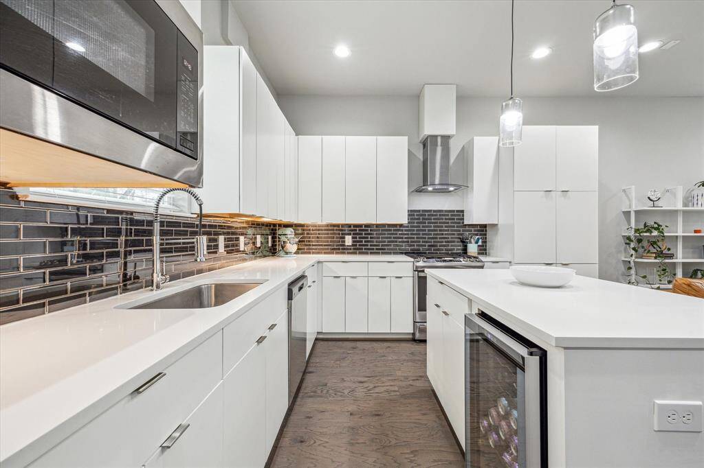 Modern kitchen with sleek white cabinetry, stainless steel appliances, and a stylish subway tile backsplash. Features a large island with pendant lighting and ample counter space, perfect for cooking and entertaining.