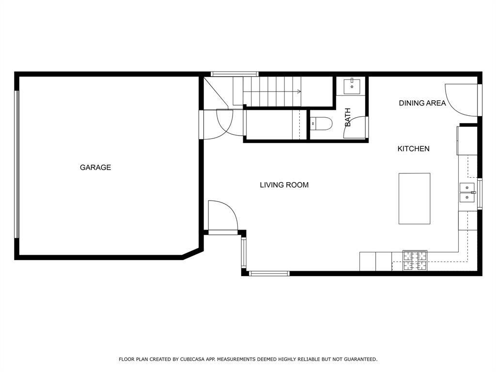 This floor plan features a spacious living room connected to a kitchen and dining area. There's a bathroom conveniently located near the stairs. The garage offers ample space for vehicles or storage. The layout is open and functional, ideal for comfortable living and entertaining.