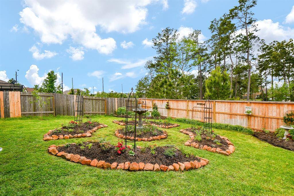 VIEW OF BACKYARD AND ALL THE TREES BEHIND THE FENCE ON THE GREENBELT AREA. SELLER WILL REMOVE CENTER FLOWER BEDS AND RETURN TO SOD IF BUYER PREFERS