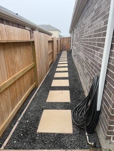 RIGHT SIDE OF HOME WITH LEVELED PAVERS AND CRUSHED ROCK LEADING TO GATE