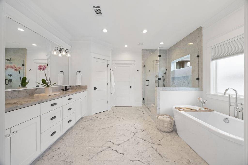 Step into a truly luxurious primary bath—complete with marble floors, a freestanding soaking tub, frameless glass shower, and dual vanities. Thoughtful design and timeless finishes make this space a standout.