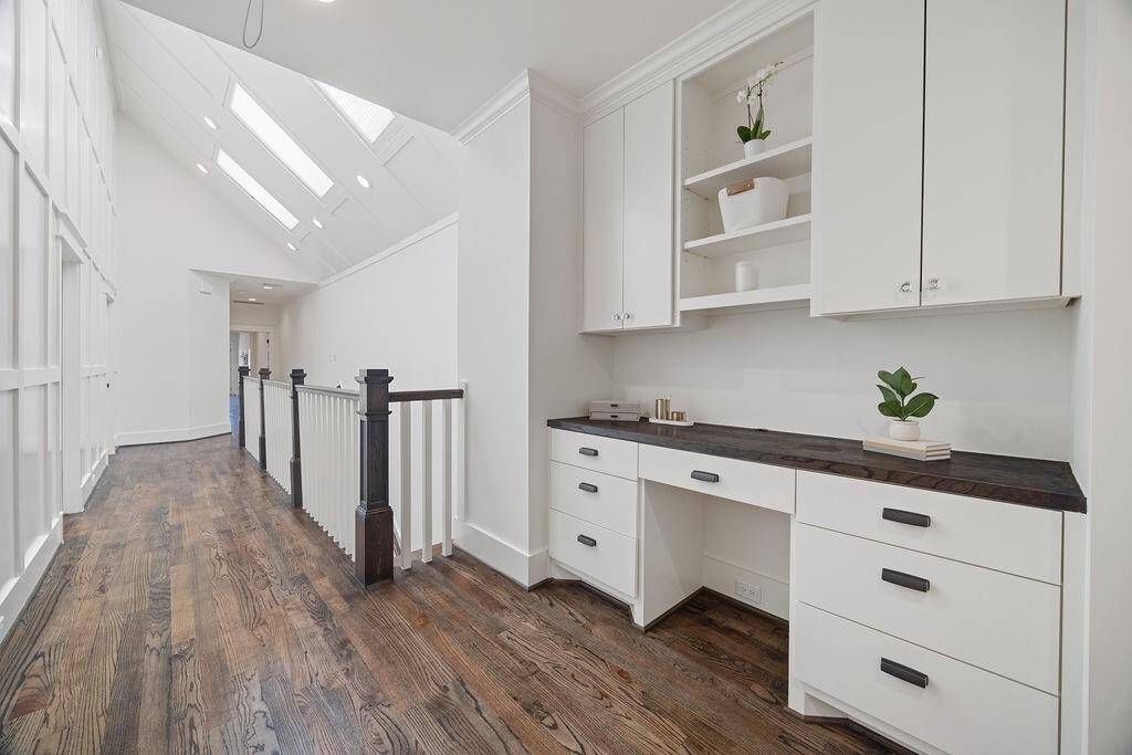 The second-floor hallway stuns with soaring ceilings, architectural features, and a row of skylights that fill the space with natural light.