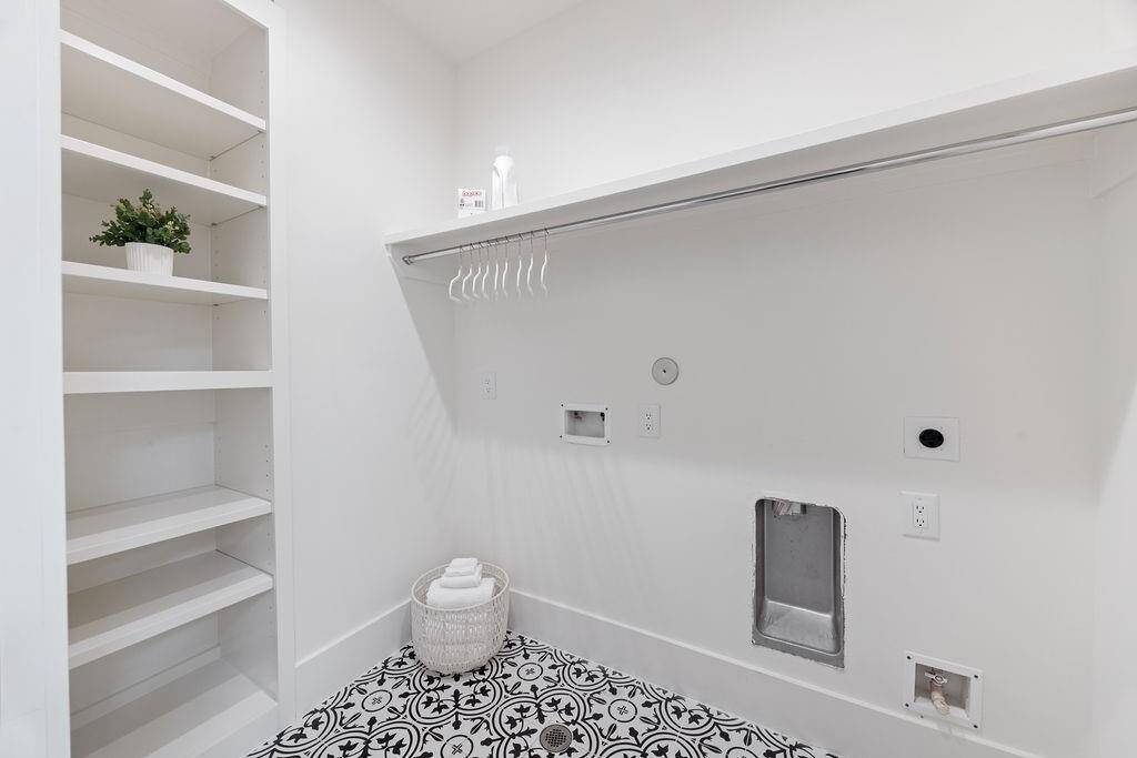 Spacious upstairs laundry with built-in shelving, hanging space, and patterned tile flooring—beautiful and functional.