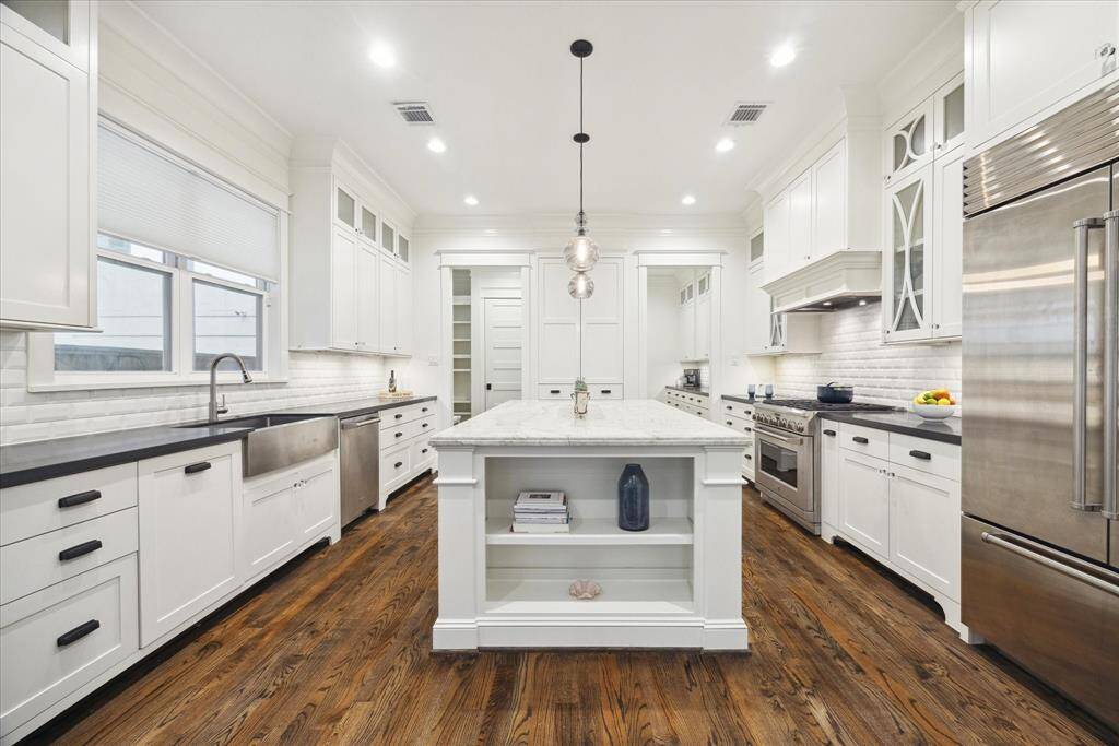 This stunning kitchen is the heart of the home, featuring a wide marble island with seating, floor-to-ceiling custom cabinetry, and premium appliances including a Sub-Zero refrigerator and a 6-burner gas range. The open layout connects to the dining and living areas, making it perfect for both everyday living and entertaining.