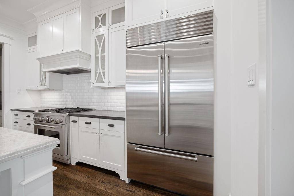 This kitchen showcases premium appliances, including a Sub-Zero refrigerator and GE Monogram gas range, both integrated into custom cabinetry, offering functionality with a sleek, professional aesthetic.