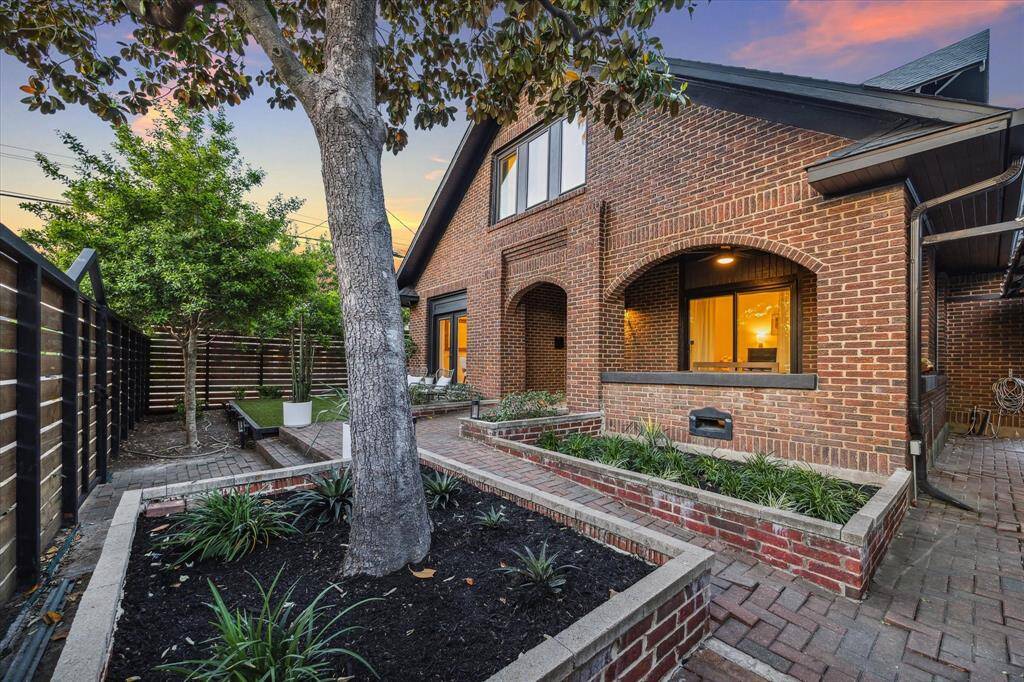 Alternate view of front porch and front lawn with lush mature landscaping.