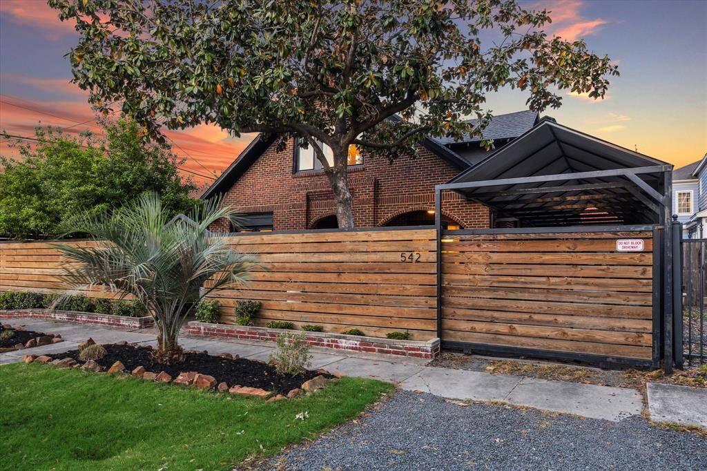 Welcome to 542 Arlington! View of automatic gate, additional gravel parking and professional landscaping.