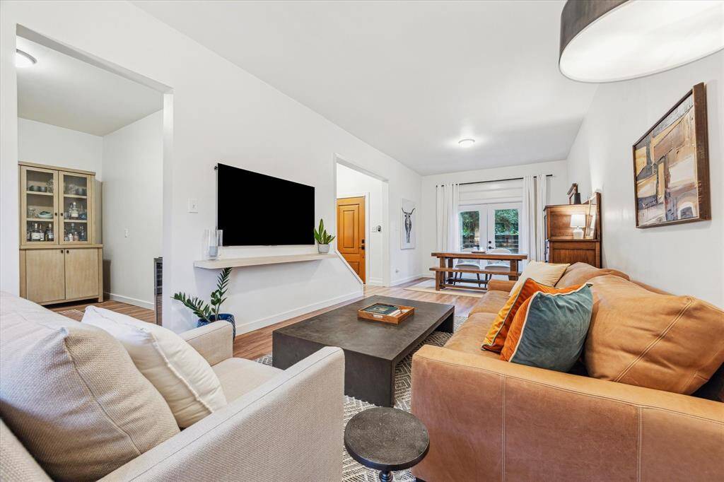 A living room filled with natural light overlooking front lawn and back deck.