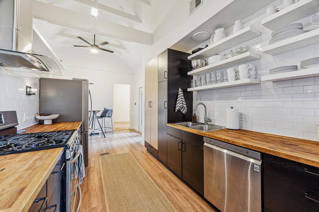 The chef’s kitchen has modern cabinets, sprawling butcher block counters, soaring cathedral ceilings, stunning vinyl plank floors and excess of natural light.
