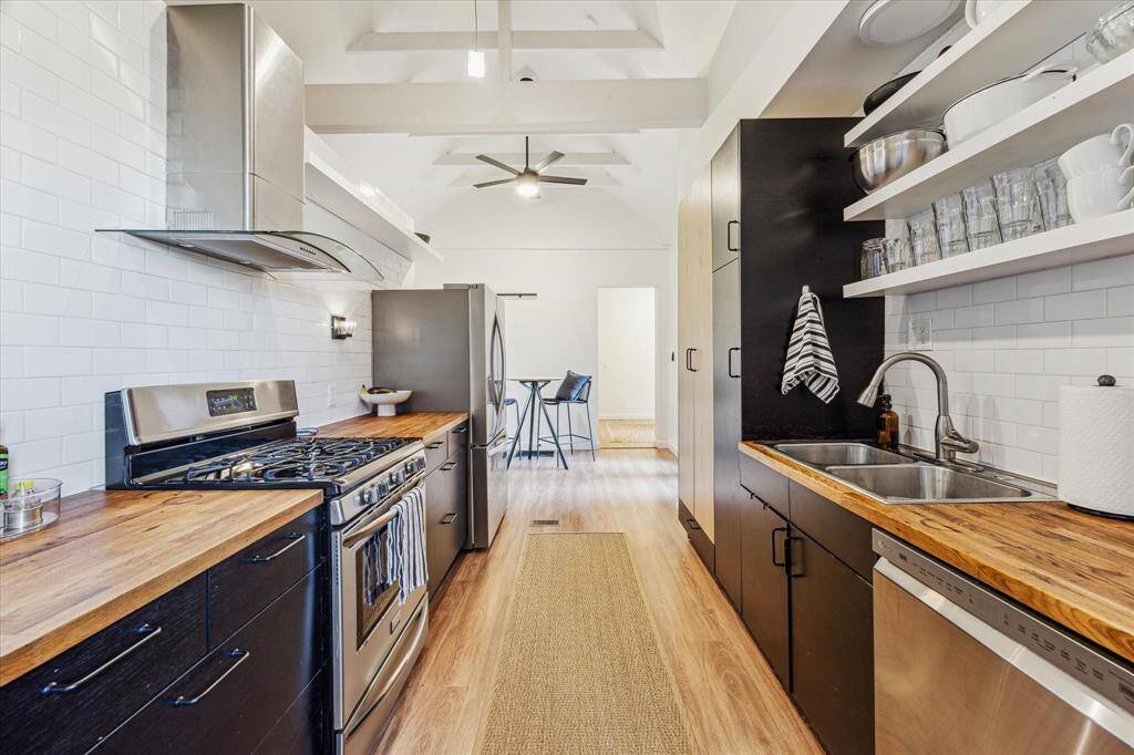 Alternate view of kitchen showcasing open shelving and abundance of cabinet storage.