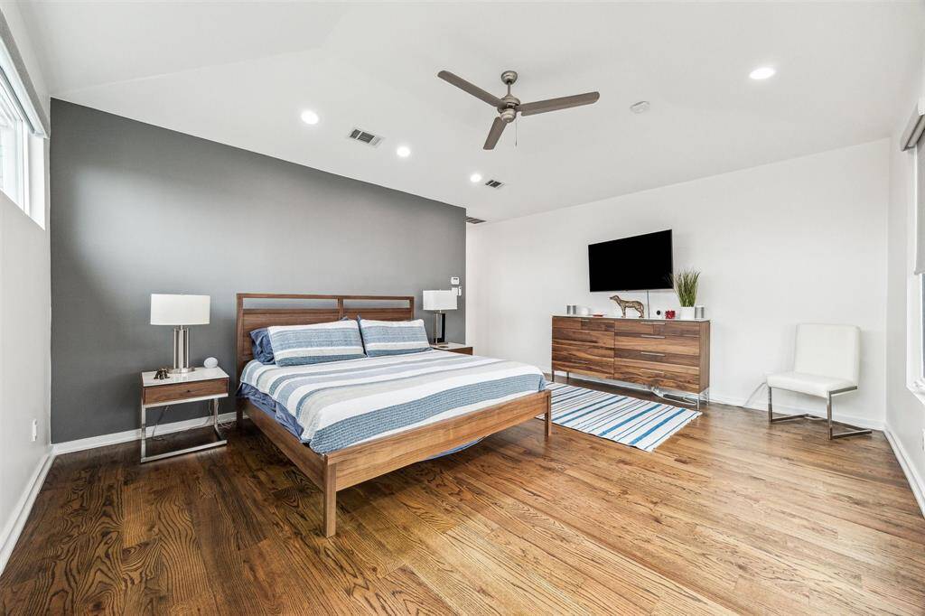 Bright master bedroom with freshly painted walls, warm wood flooring, and abundant natural light.