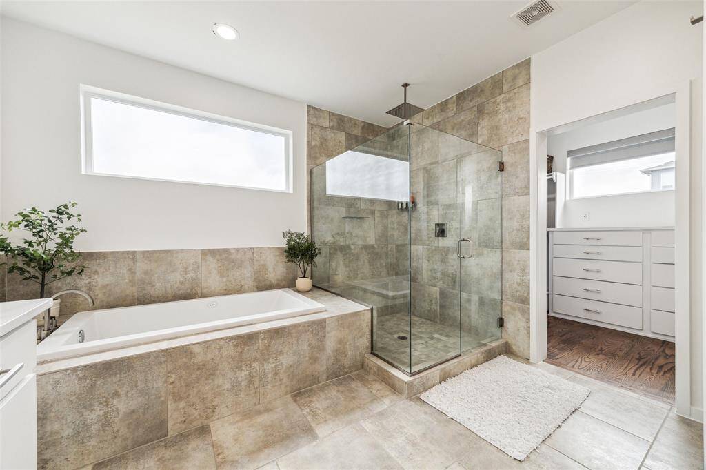 Luxurious bath featuring a spacious bathtub and a sleek glass-enclosed shower for a spa-like experience.