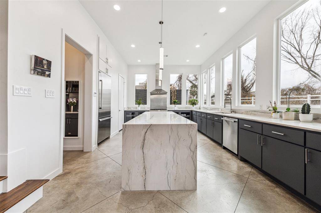Stunning kitchen with quartzite countertops, waterfall island, custom pullout features, LED pendants, and stylish bar area.
