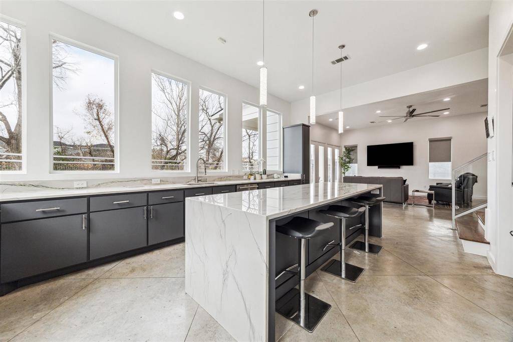 Exquisite kitchen featuring new quartzite countertops, custom waterfall island, and pullouts for waste and recycling.