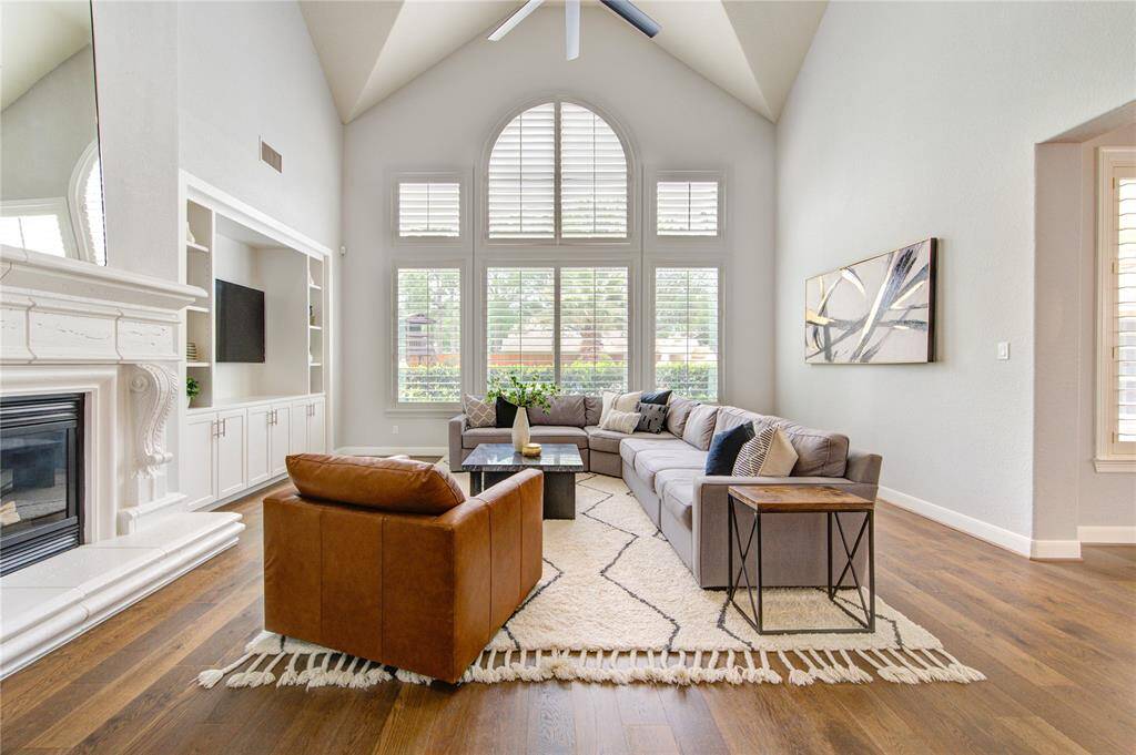 The heart of the home features dramatic windows flooding the space with light, a cozy fireplace and views of the lush backyard retreat