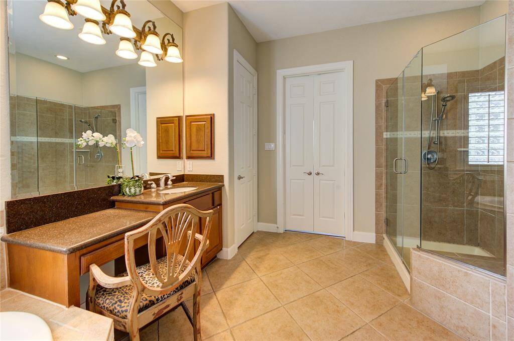 Frameless glass shower and sleek tilework elevate this ensuite bath creating a true retreat experience