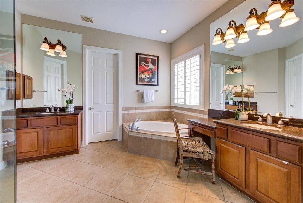 Spa-like primary bath featuring a deep soaking tub and dual vanities