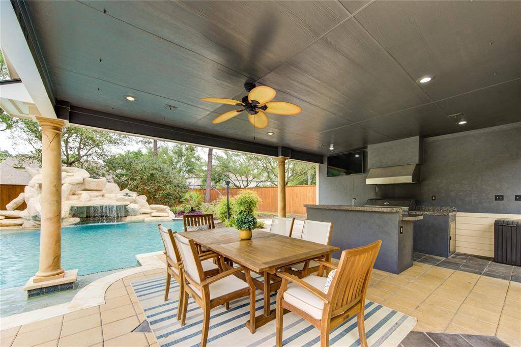 Covered outdoor kitchen and bar equipped with built-in grill and prep space—perfect for alfresco entertaining