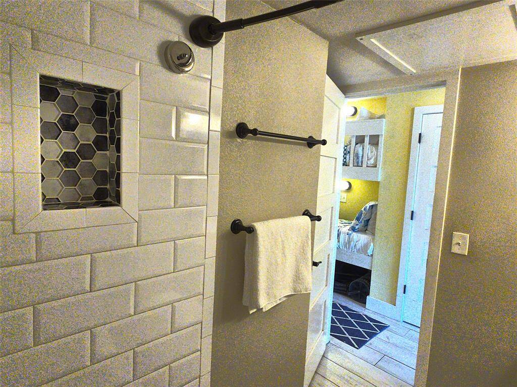 A modern bathroom with white subway tile and a hexagonal tile shower niche. It has a doors leading to the bedroom and main hallway, creating a seamless connection between the spaces.