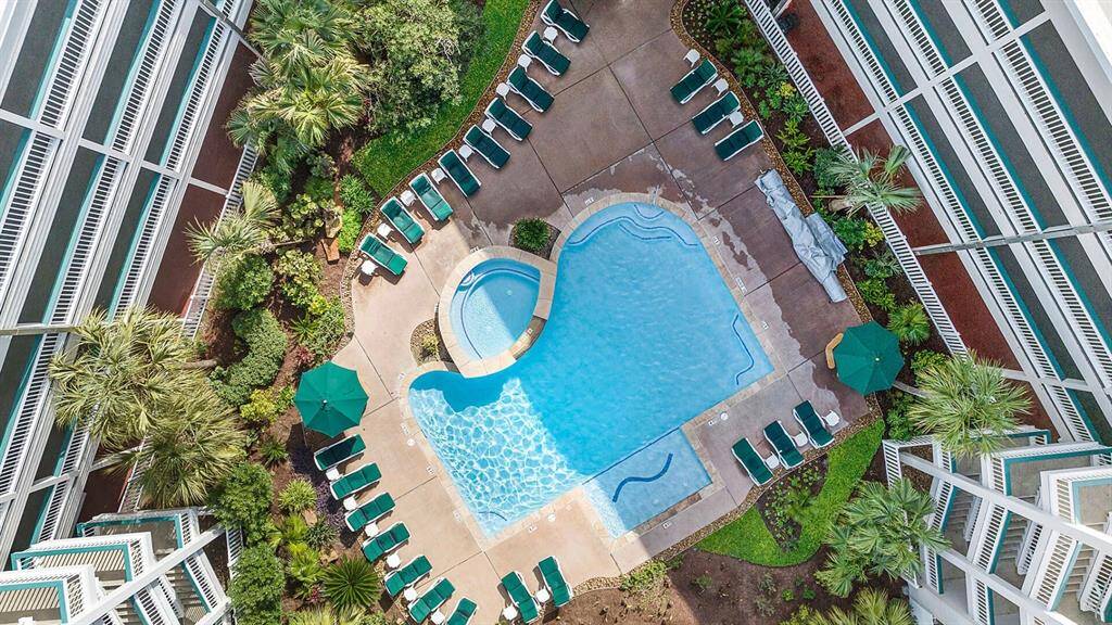 Aerial view of another Casa del Mar pool area surrounded by lush greenery and lounge chairs. Ideal for relaxation and entertaining, this inviting space offers both a main pool and a smaller, circular pool.