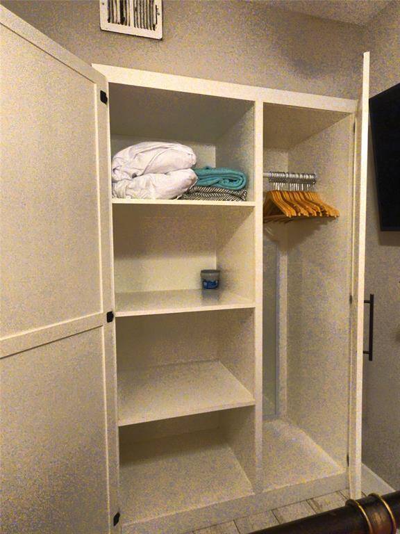 Built-in closet with open shelves and a hanging rod, offering ample storage space for clothes and linens.