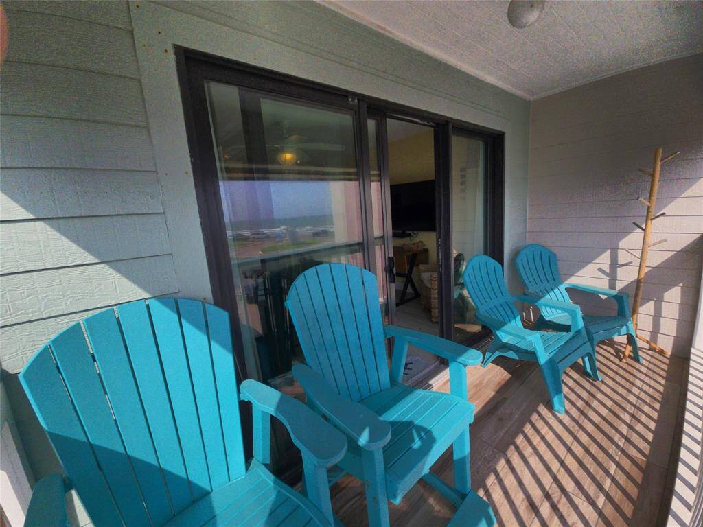 Charming balcony with vibrant turquoise Adirondack chairs, offering a cozy space for relaxation. Sliding glass doors provide easy access to the indoors, enhancing the flow between outdoor and indoor living. Ideal for enjoying a morning coffee or evening sunset.