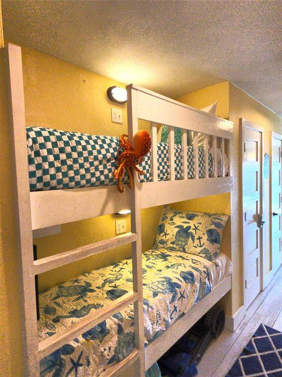 This photo features a cozy bunk bed setup in a hallway with nautical-themed bedding and a playful octopus decoration. The space is bright with wall-mounted lighting and tv.