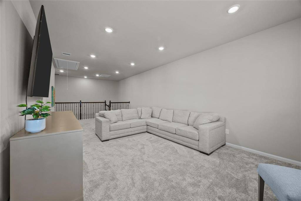 Huge carpeted living area/gameroom/flex space with recessed lighting.