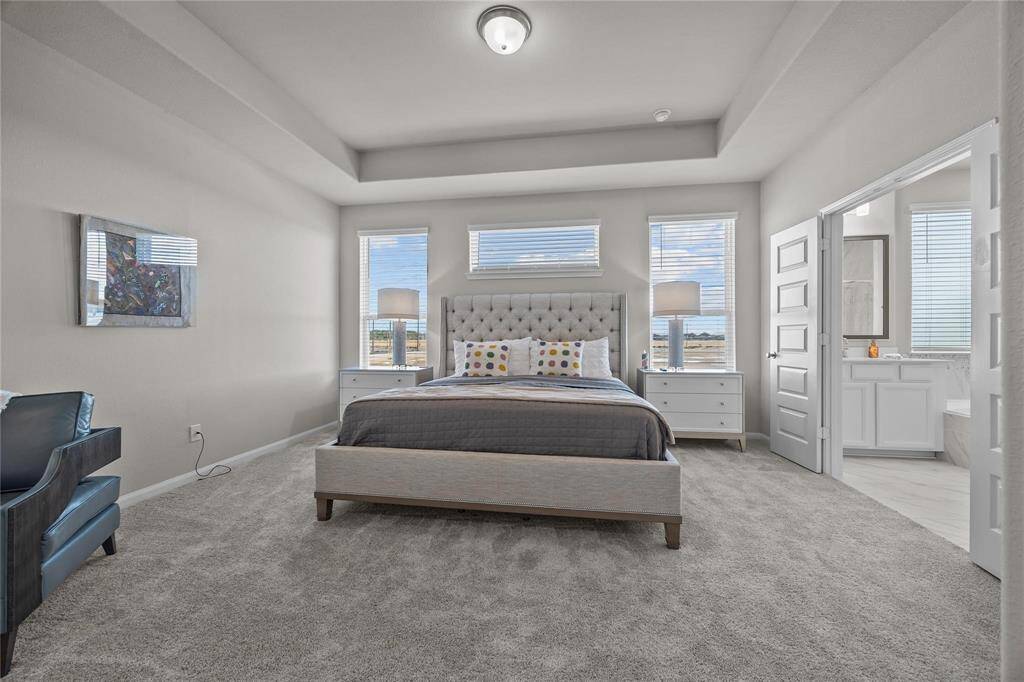 This spacious primary bedroom upstairs features plush carpeting, room for a king size bed. Ample natural light from multiple windows. It includes a cozy seating area, and a walk-in closet for added convenience.