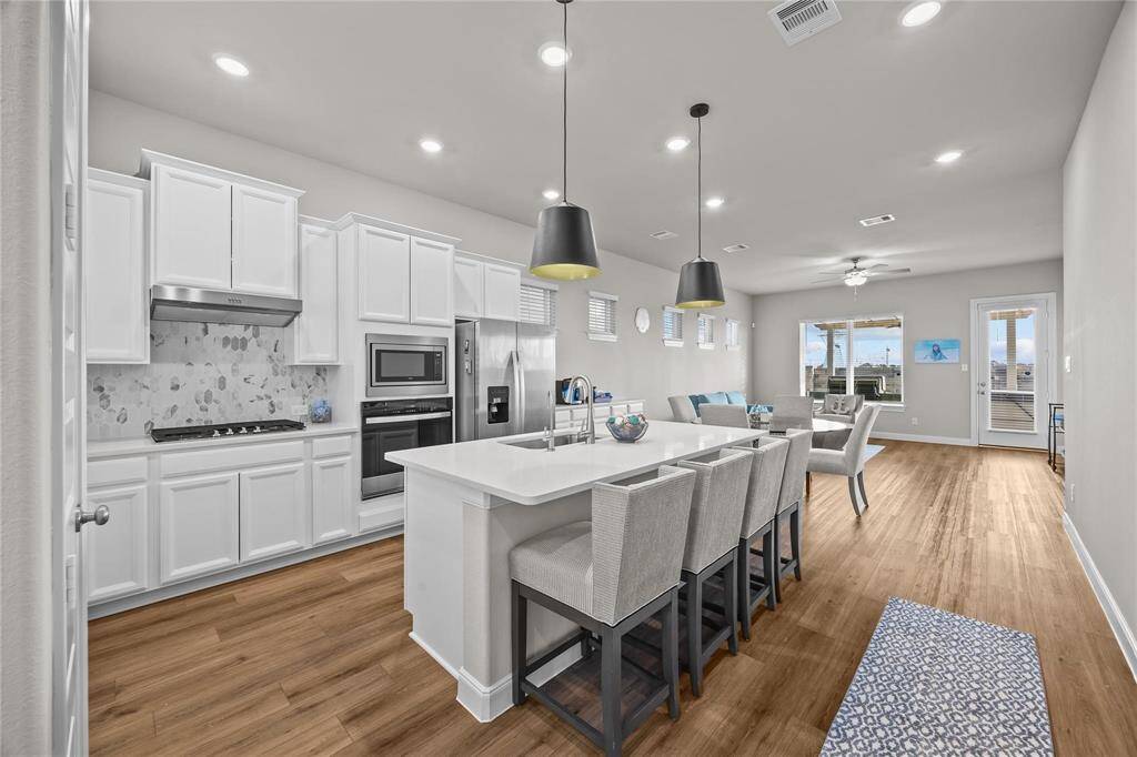 Large island with bar seating. The living space is bright with natural light from large windows and a door leading to the extended patio with Hot Springs Therapeutic hot tub.
