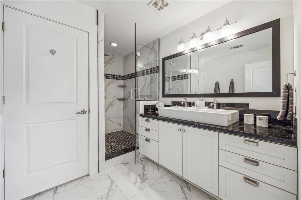 The primary bath features a double sink, spacious walk-in shower with frameless glass and a water closet.
