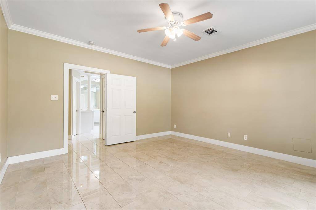 Another view of the primary bedroom with crown molding and spacious en suite bath.