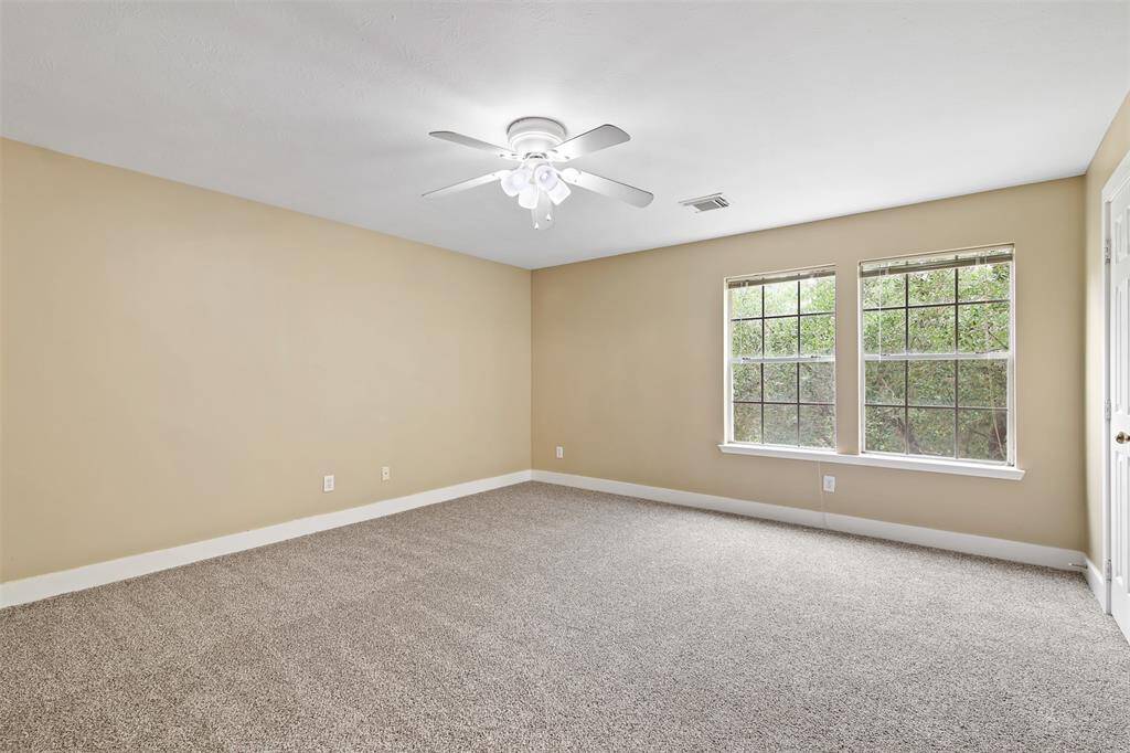Secondary bedroom features carpet, ceiling fan and picture windows.
