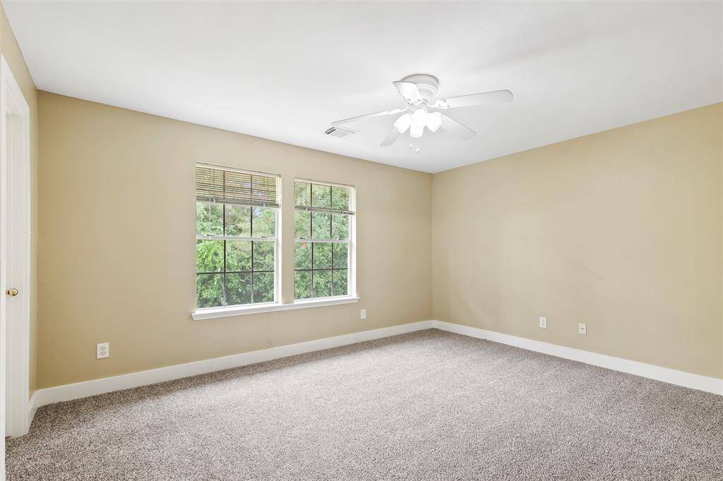 Another additional bedroom upstairs with carpet and ceiling fan.