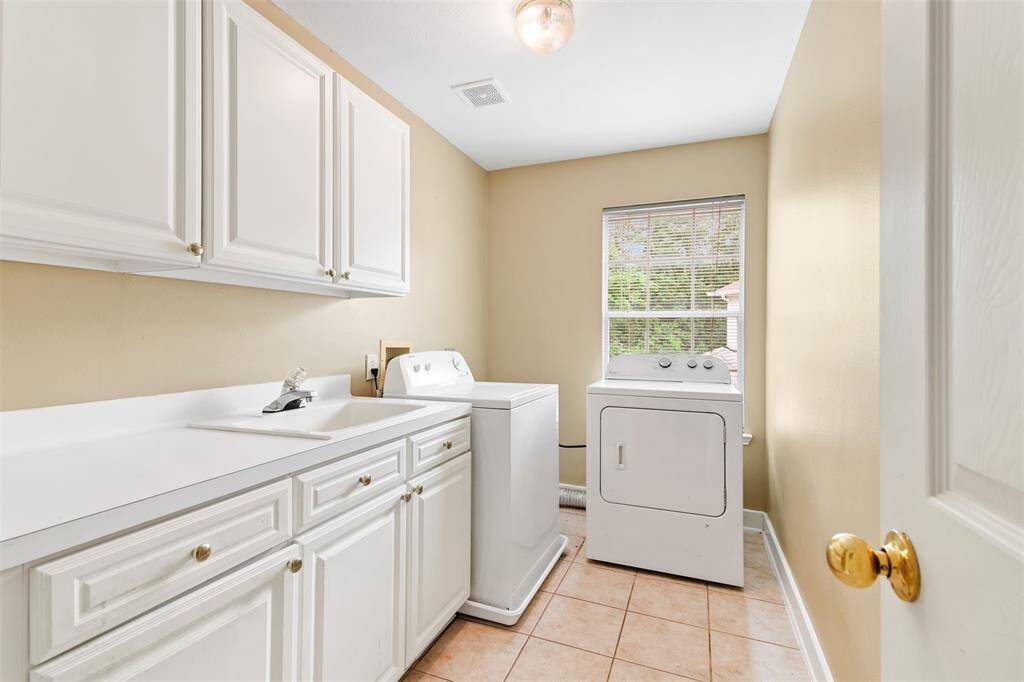 Spacious laundry room features built in storage, sink and washer and dryer.