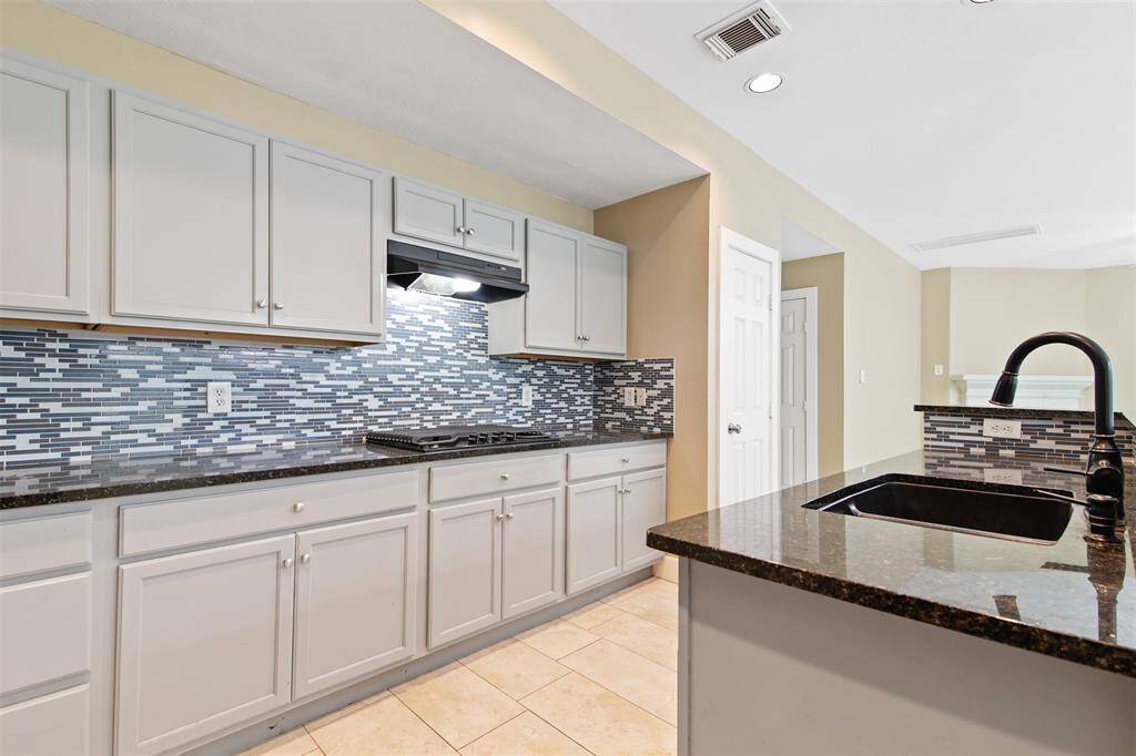 Spacious kitchen features granite counter-tops and decorative tile backsplash.