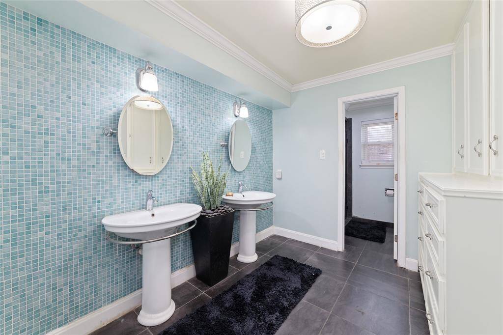 Unique full bath with penny tile and double pedestal sinks. A touch of charm meets practical function here.