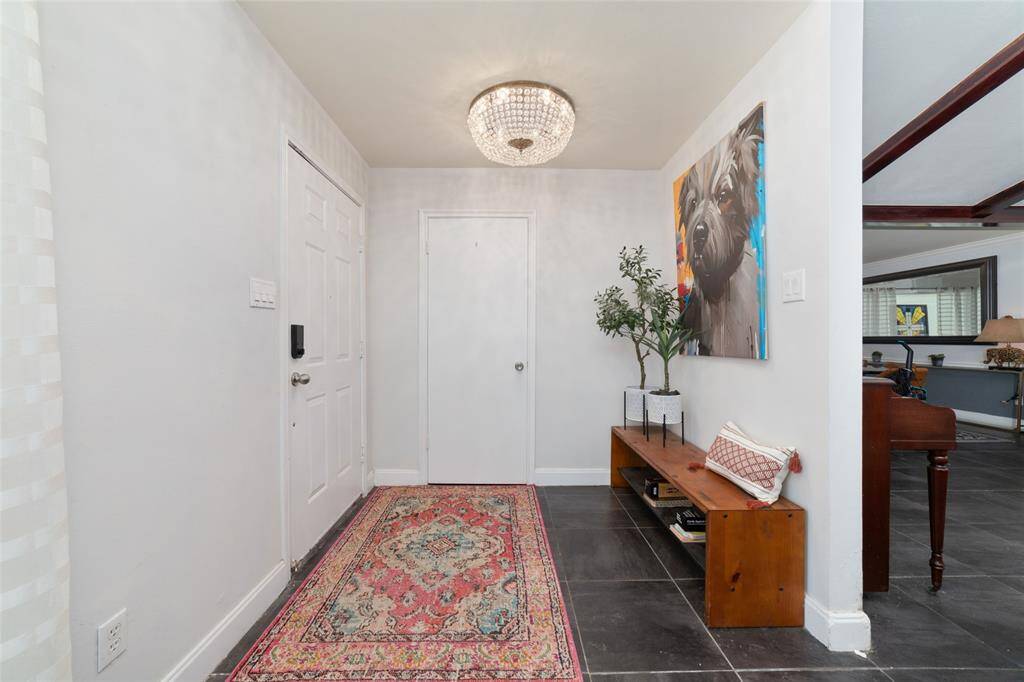 Bright entry hallway with timeless tilework and a statement chandelier. A thoughtful introduction to the home's character and style.
