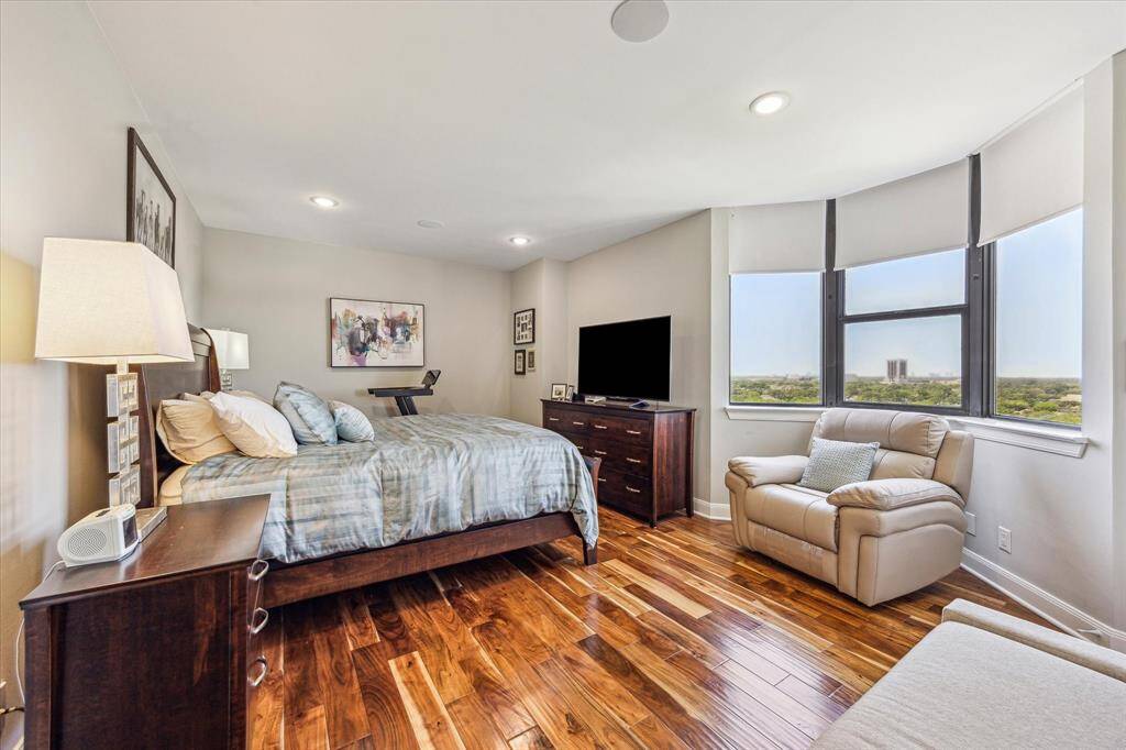The spacious primary bedroom features large windows that flood the space with natural light, while electric shades add a touch of luxury—letting you enjoy serene green views each morning without ever leaving the comfort of your bed.