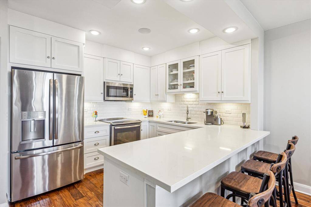 Bright and airy, the kitchen showcases crisp white finishes, high-end GE Profile appliances, and soft under-cabinet lighting that creates a warm, welcoming ambiance.