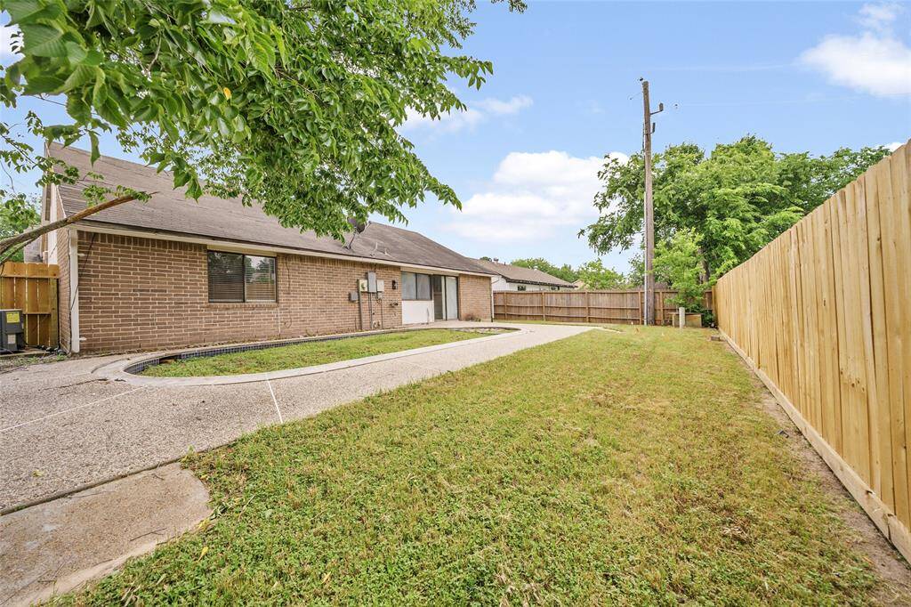 The yard is bordered by a wooden fence and features mature trees, offering a private outdoor space.