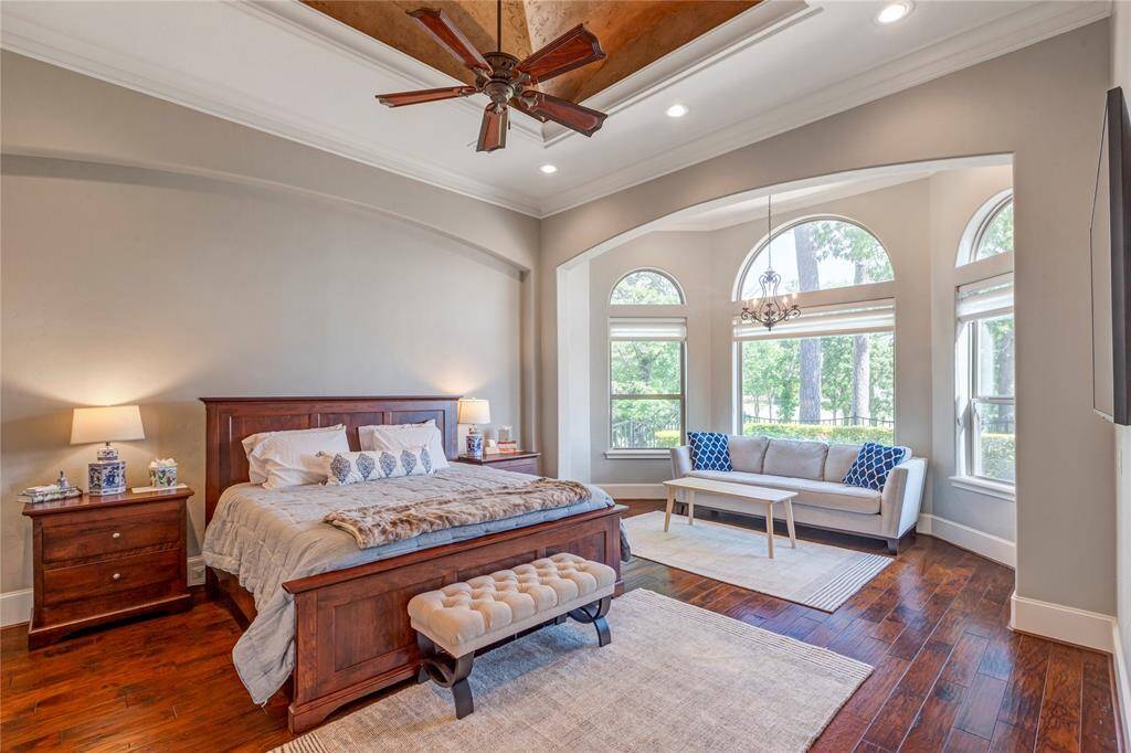 This primary bedroom has a setting area and coffered ceiling with excellent views of the golf course and Lake Conroe.