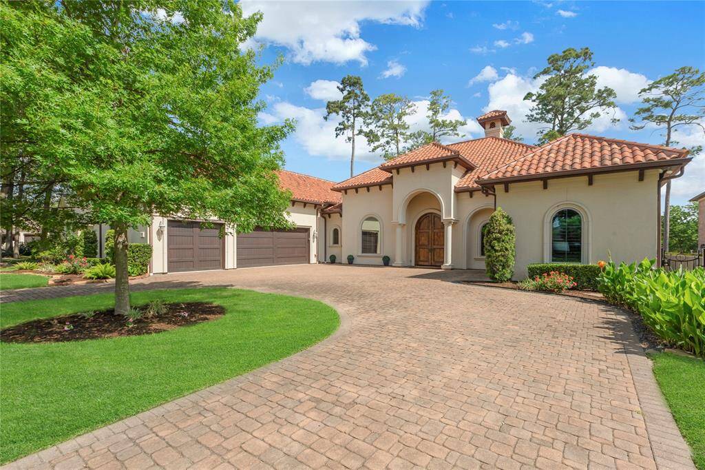 Circle driveway with 3 car garage and paver driveway with large double door entryway.
