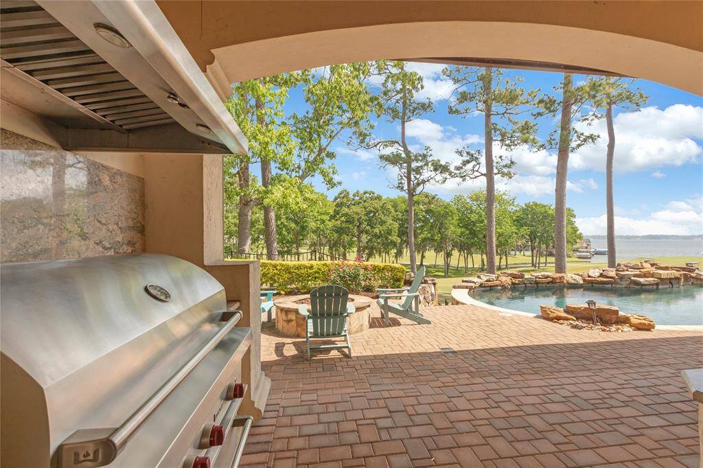 Outdoor kitchen area with Wolf Grill, Vent hood, and granite counter tops.  Fire pit and wonderful golf and water views.  Pavers in the patio area.