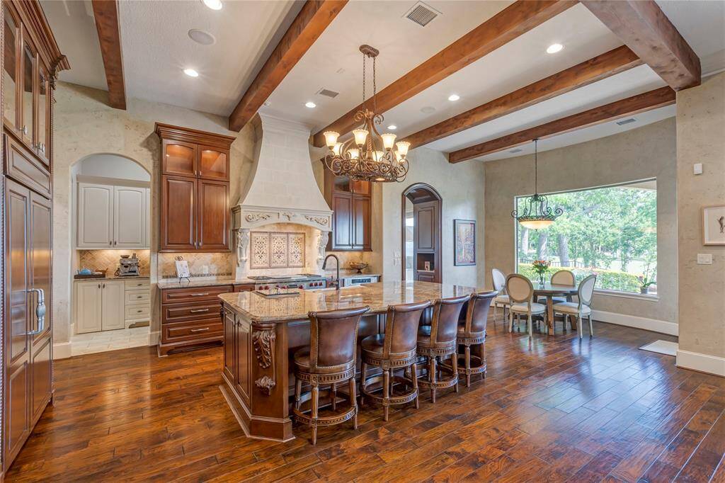 Kitchen has wooden beams with large island that has sink, steamer, & dishwasher.  Sub Zero Refrigerator, Wolf Gas Double Oven Cooker.