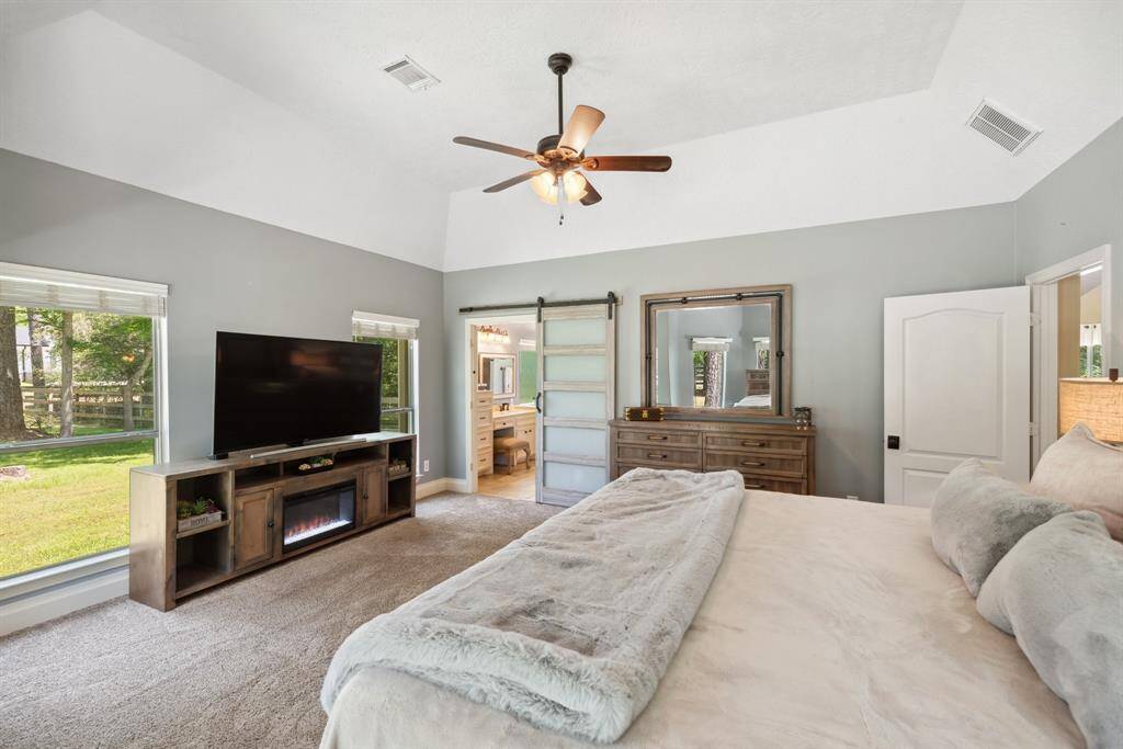 This secondary bedroom measures appox 14x12 and features large windows, custom blinds for privacy, cozy carpeting, ceiling fan with lights, crown moldings, and a large reach-in closet.