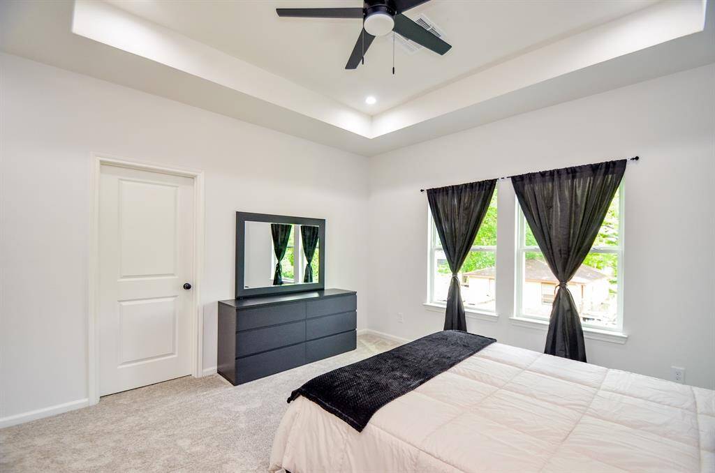 This cozy master bedroom featuring carpeted flooring and natural light from large windows. Second walk-in closet is behind the door.