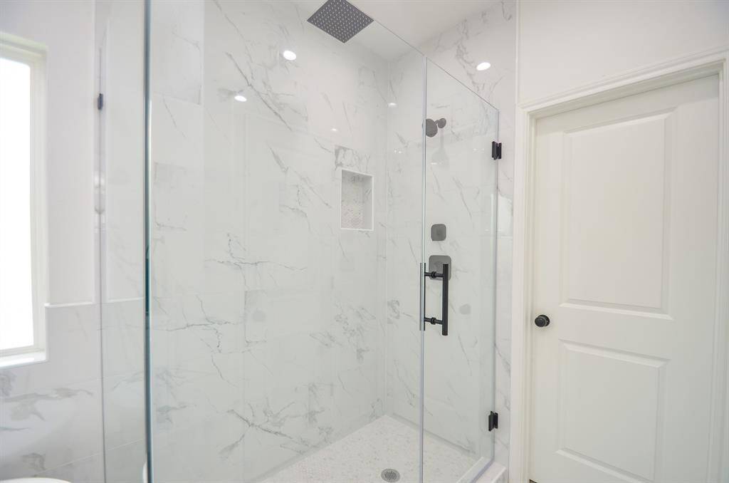 This large enclosed glass shower with mosaic tile floor and shower niche are stylish and create a spacious like feel.