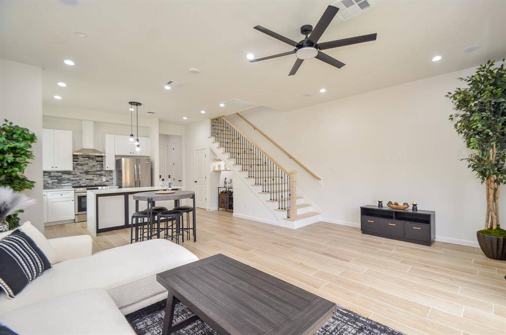 This modern open-concept living area features a sleek kitchen with a center island, stainless steel appliances, and stylish backsplash. room's airy feel.